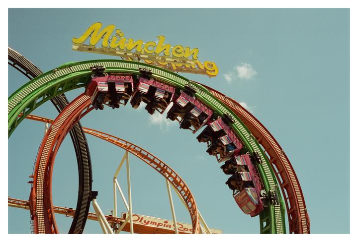 A roller coaster with people in its cars is looping upside down against a clear blue sky.