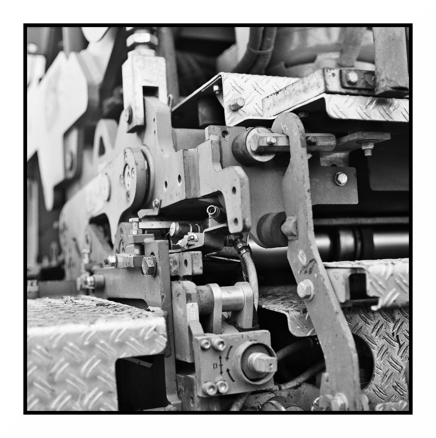 A close-up view shows the intricate mechanical components of a machine, including bolts, levers, and diamond plate textures.
