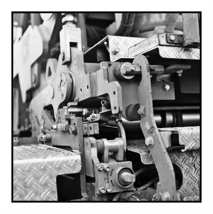 A close-up view shows the intricate mechanical components of a machine, including bolts, levers, and diamond plate textures.