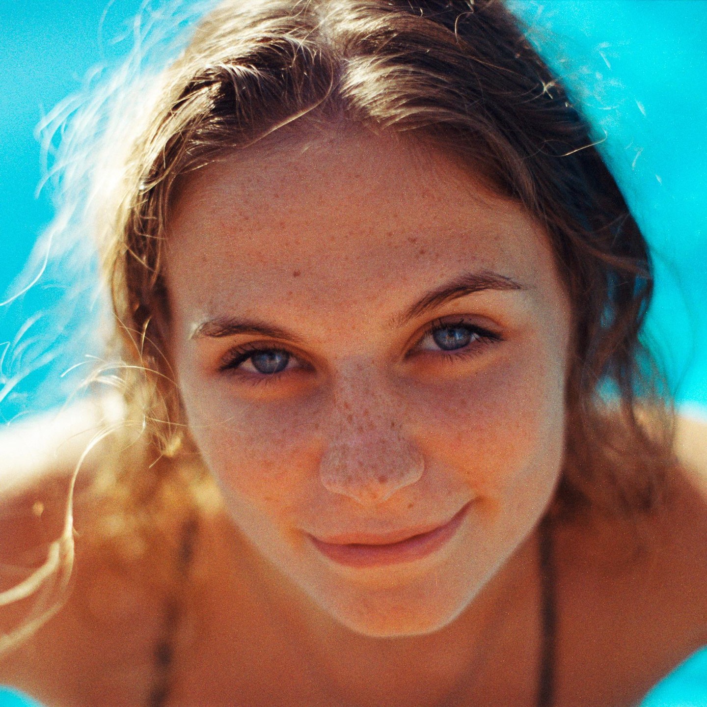 A woman with freckles and blue eyes smiles at the camera.