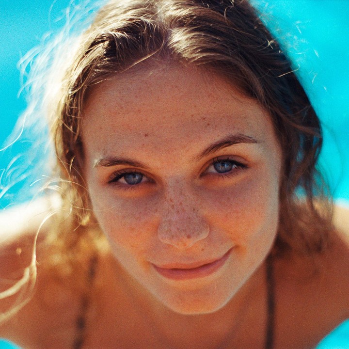 A woman with freckles and blue eyes smiles at the camera.