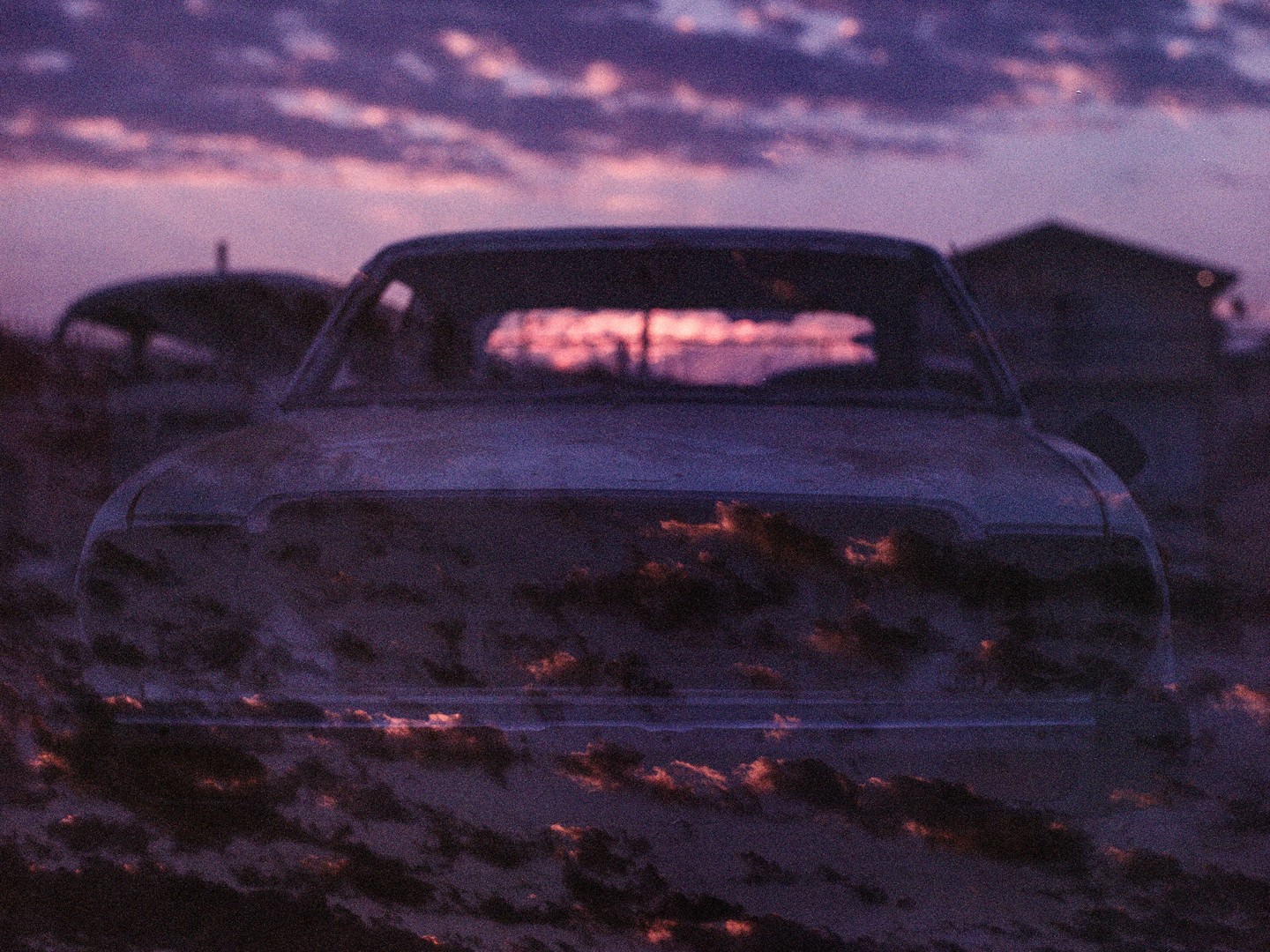 A double exposure shows a sunset over the Salton Sea reflected in the body of a car.