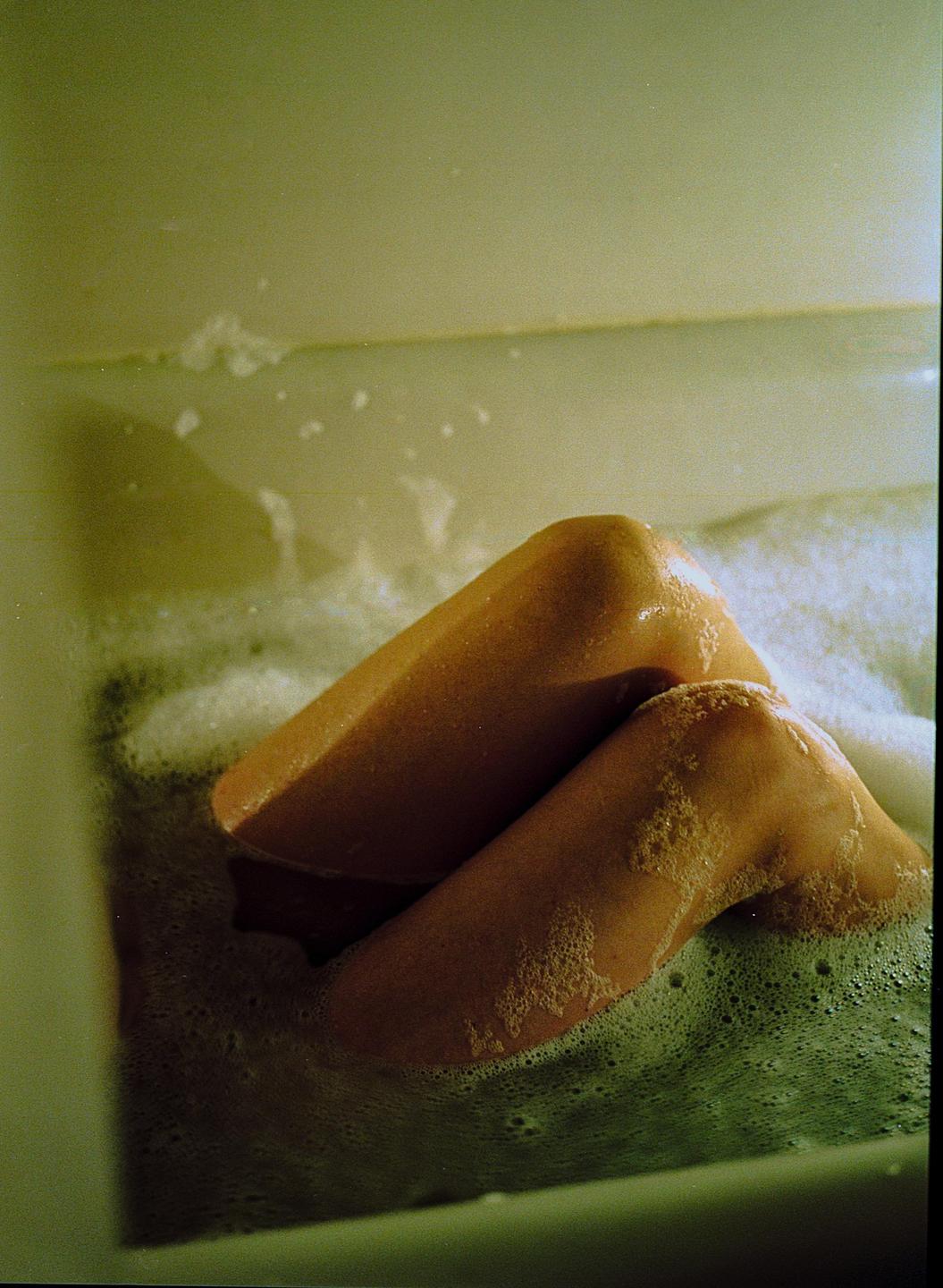 A person's legs are visible in a bubble bath.