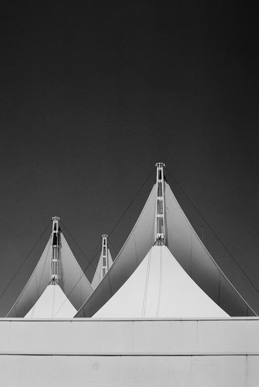 Three white tent-like structures with pointed tops are visible against a dark sky.
