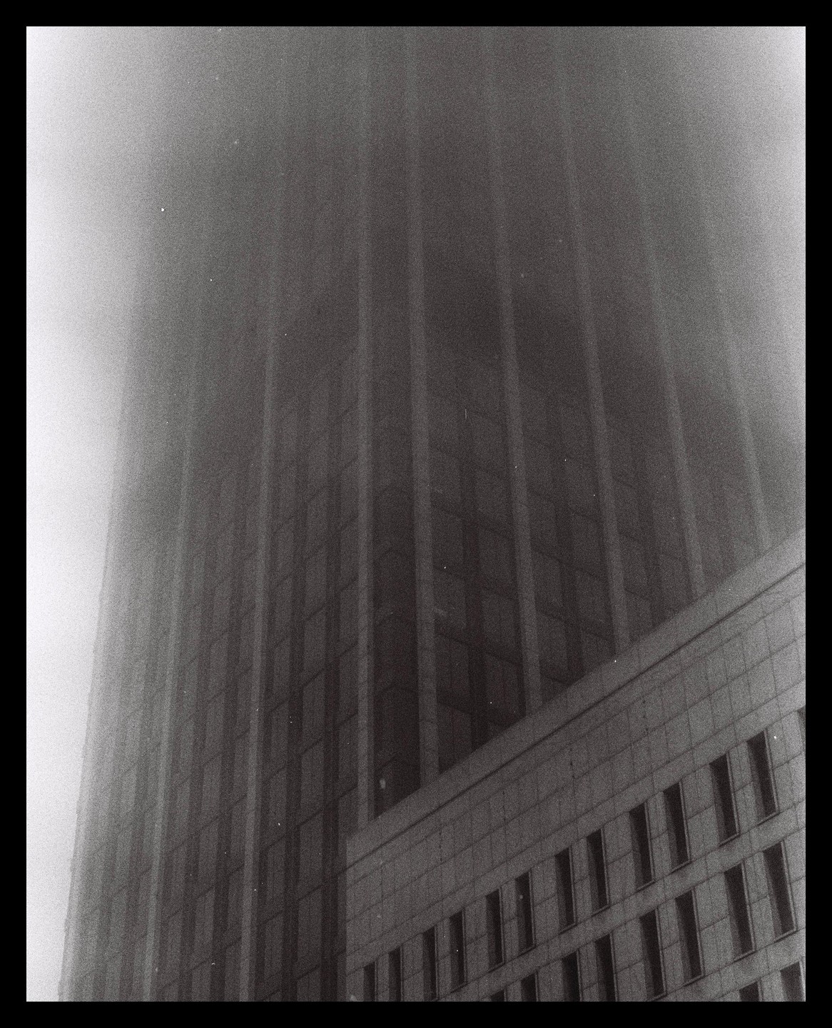 A tall building is partially obscured by a thick fog.