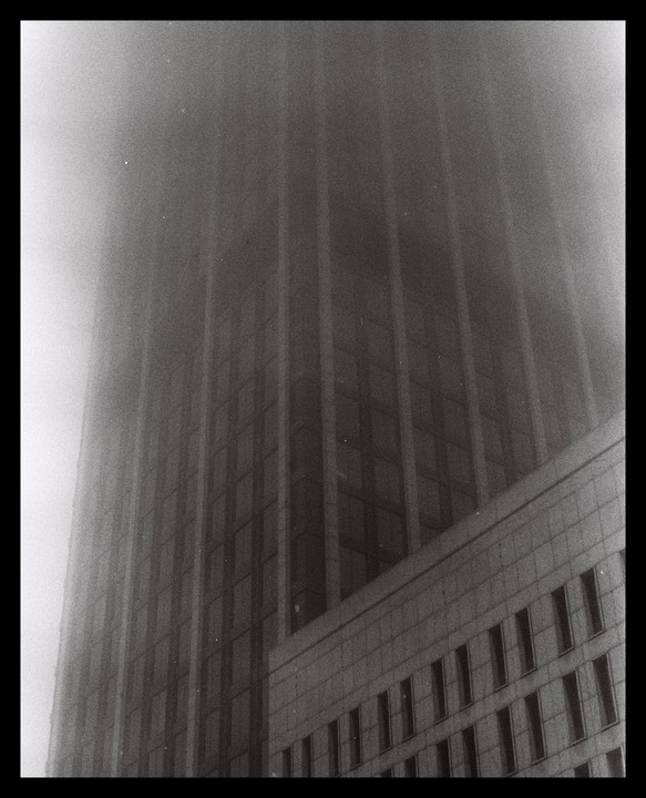 A tall building is partially obscured by a thick fog.
