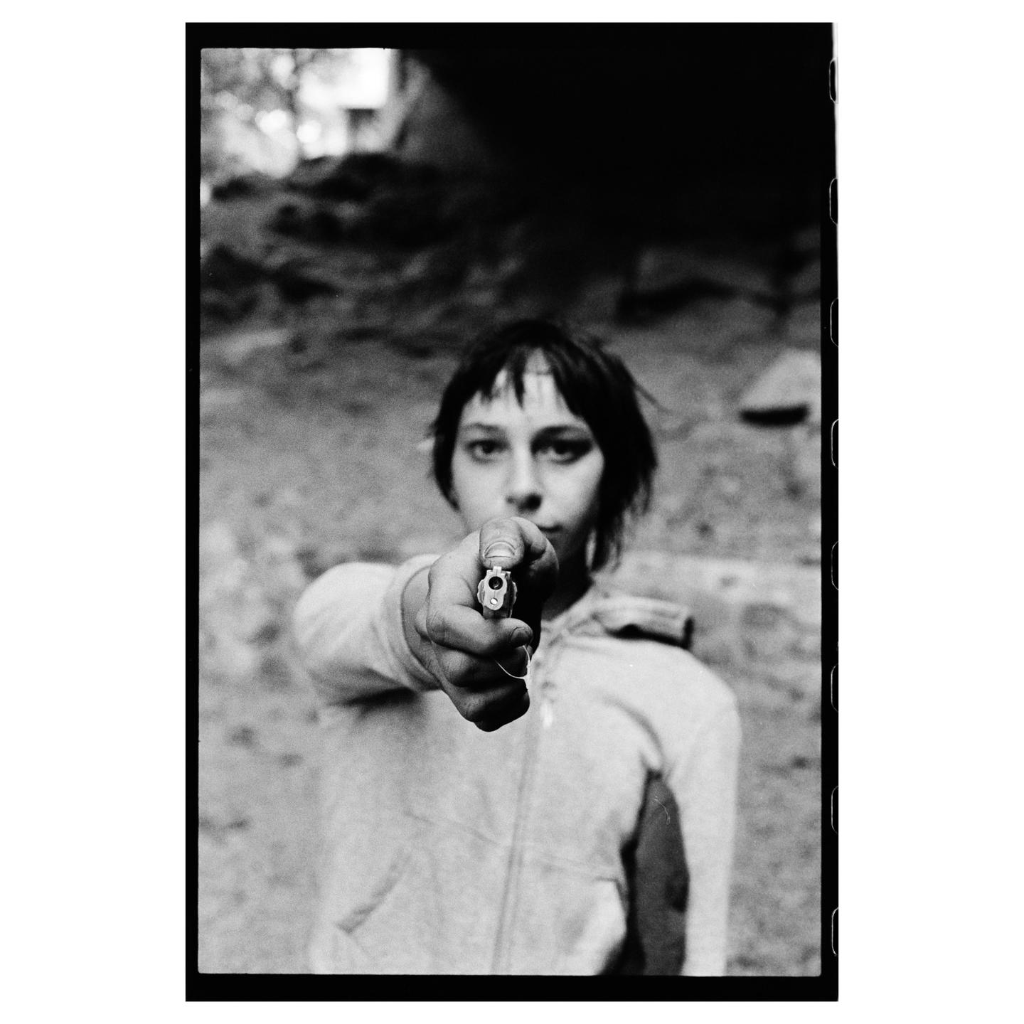 A child points a toy gun directly at the viewer.