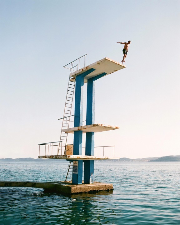A man is captured mid-air as he jumps from a diving platform into the sea.