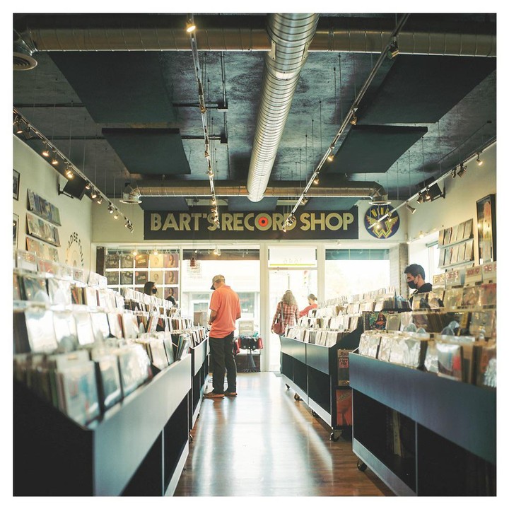 A man in an orange shirt looks at records in a record store.