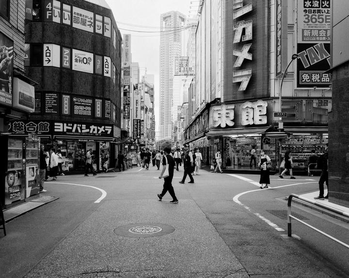 A street in a city is filled with pedestrians and tall buildings with many signs.
