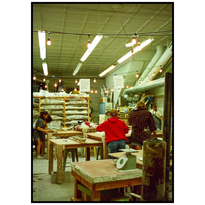 Several people are working in a pottery studio with various tools and equipment.