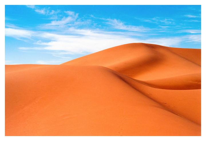 A desert landscape shows rolling sand dunes under a bright blue sky with wispy clouds.