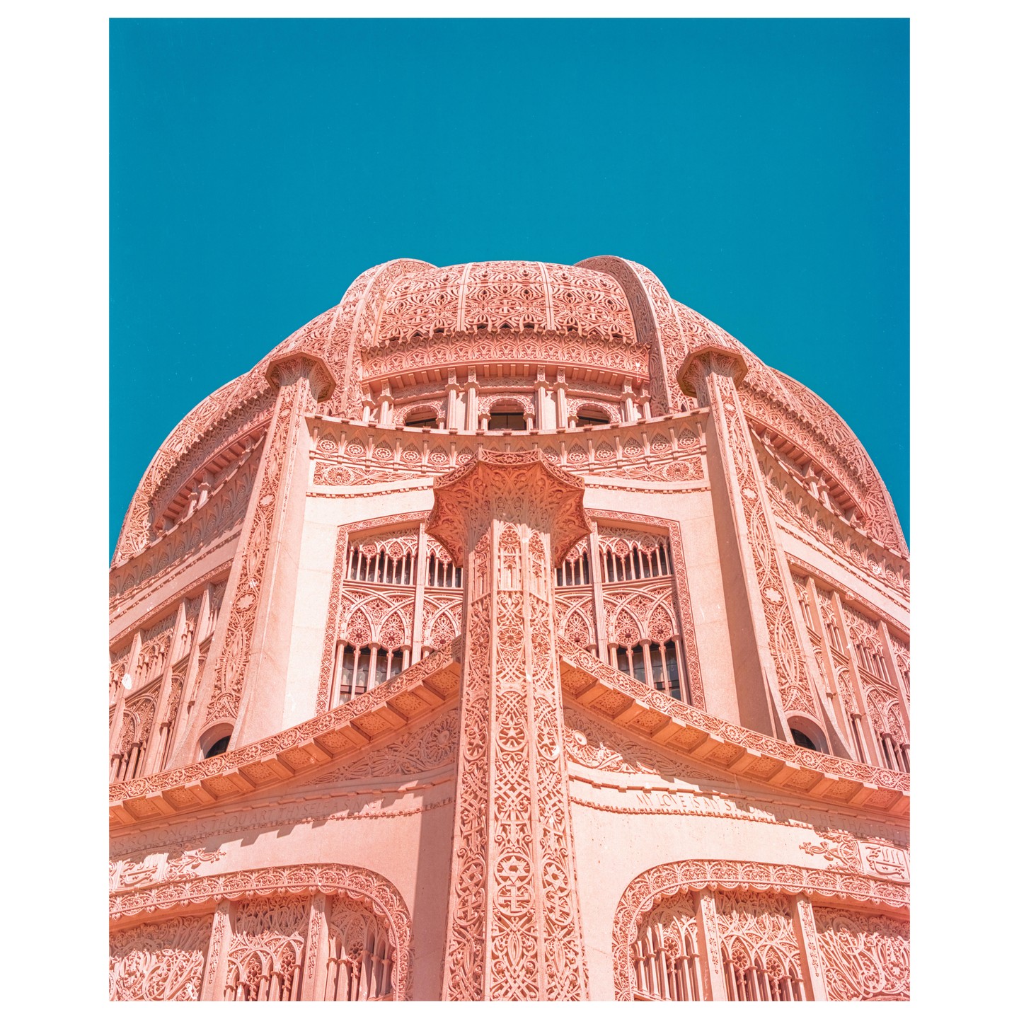 A low-angle view shows the intricate details of a large, ornate temple dome against a clear blue sky.