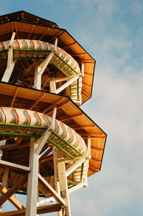 A wooden structure with a spiral slide is visible against a blue sky.