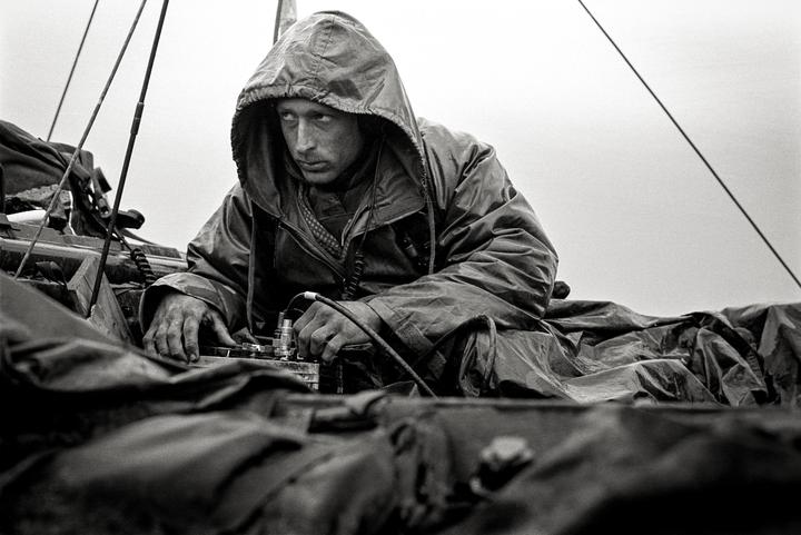 A man in a hooded jacket operates equipment with his hands.