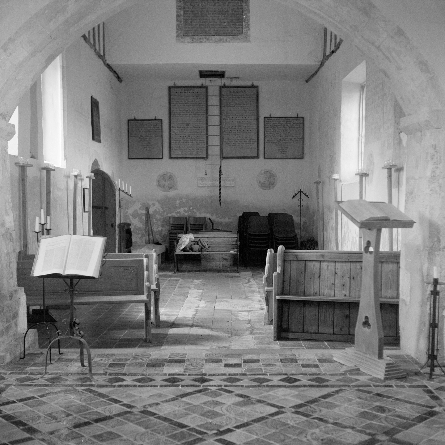 A church interior shows wooden pews, a lectern, and a patterned tile floor.