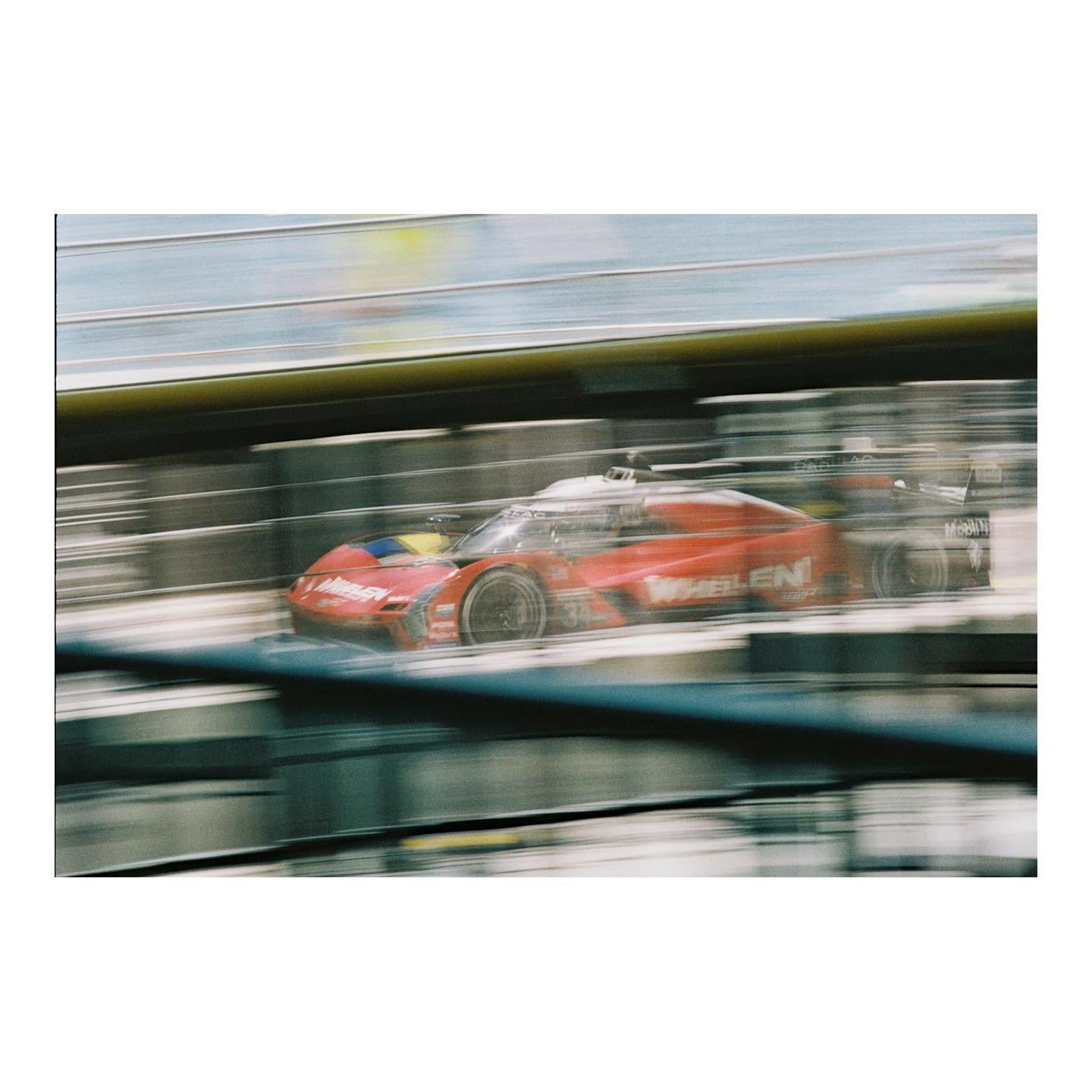 A red race car speeds past with motion blur in the background.