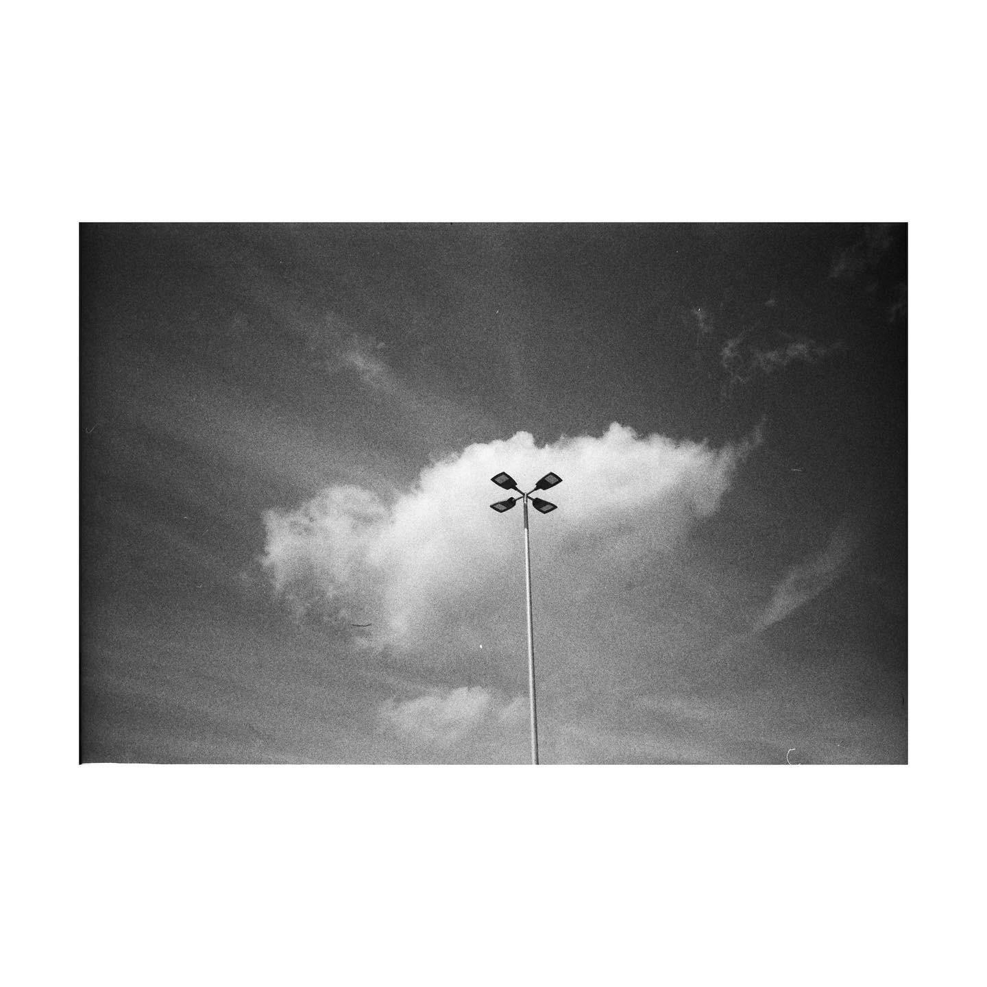 A tall light pole stands against a cloudy sky.