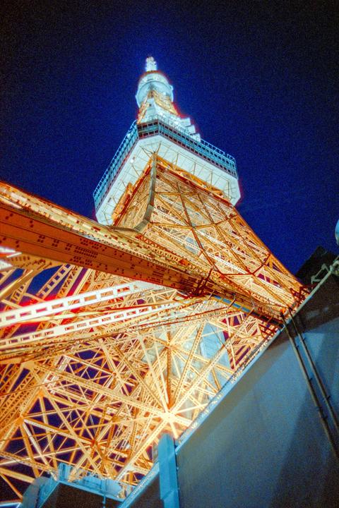 The Tokyo Tower is illuminated at night against a dark blue sky.