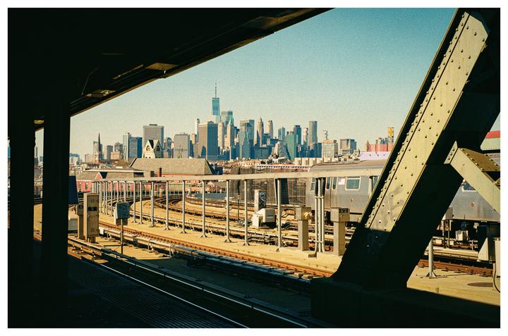 A train station with tracks and a train is visible in the foreground, with a cityscape in the background.