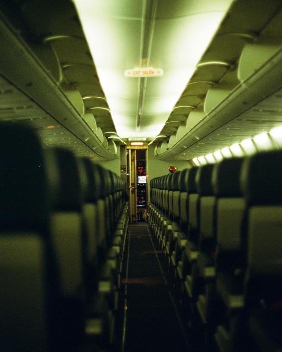 An empty airplane cabin is visible from the back, looking towards the cockpit.
