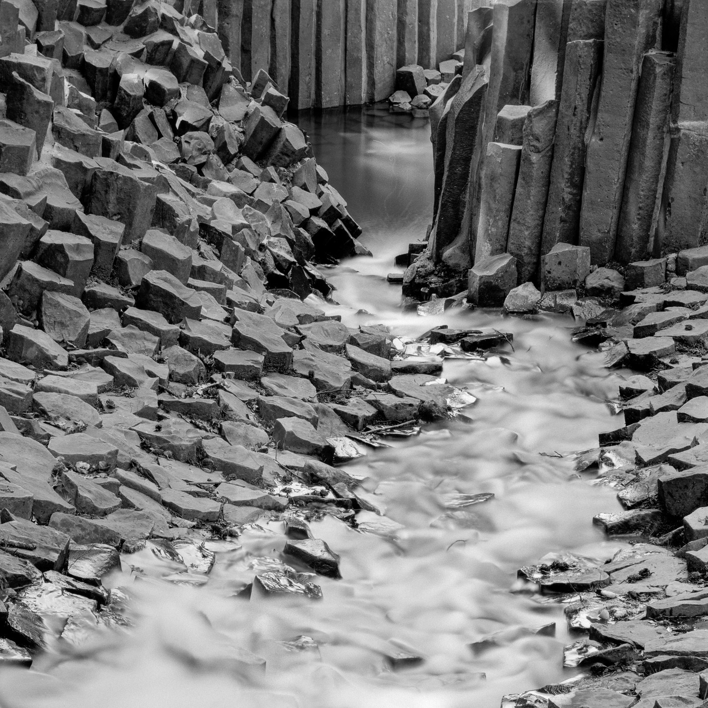 A stream flows through a canyon of hexagonal basalt columns.