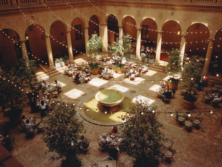 A cafe courtyard with string lights and a fountain is filled with people dining at tables.