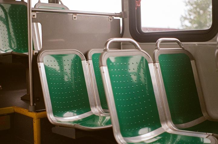 Several empty green and silver bus seats are visible next to a window.