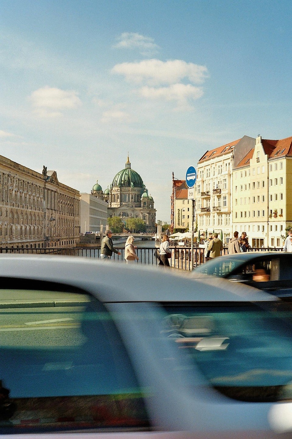 A street view of Berlin with the cathedral in the background and cars in motion in the foreground.