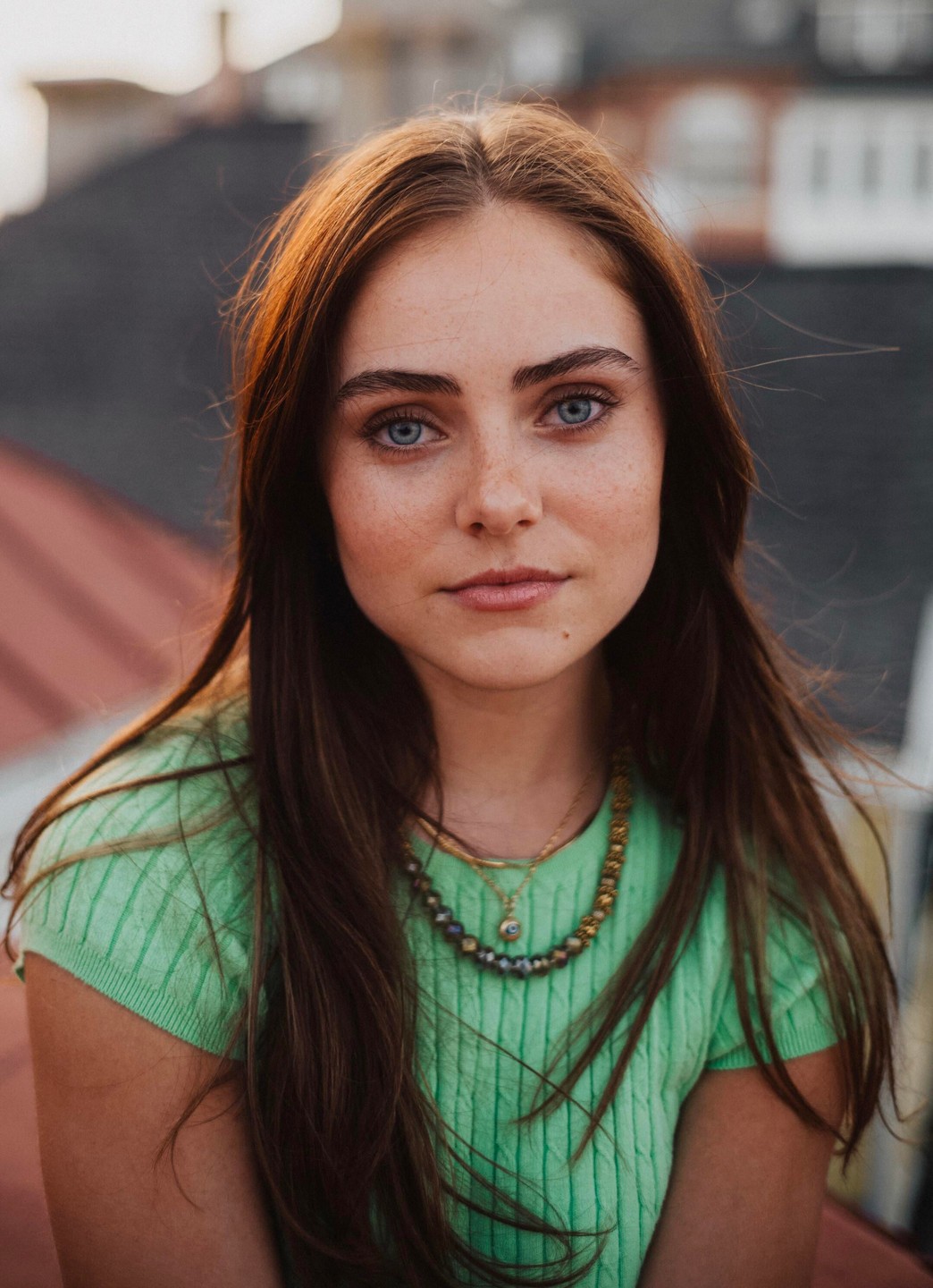 A woman with long brown hair and blue eyes looks directly at the viewer.