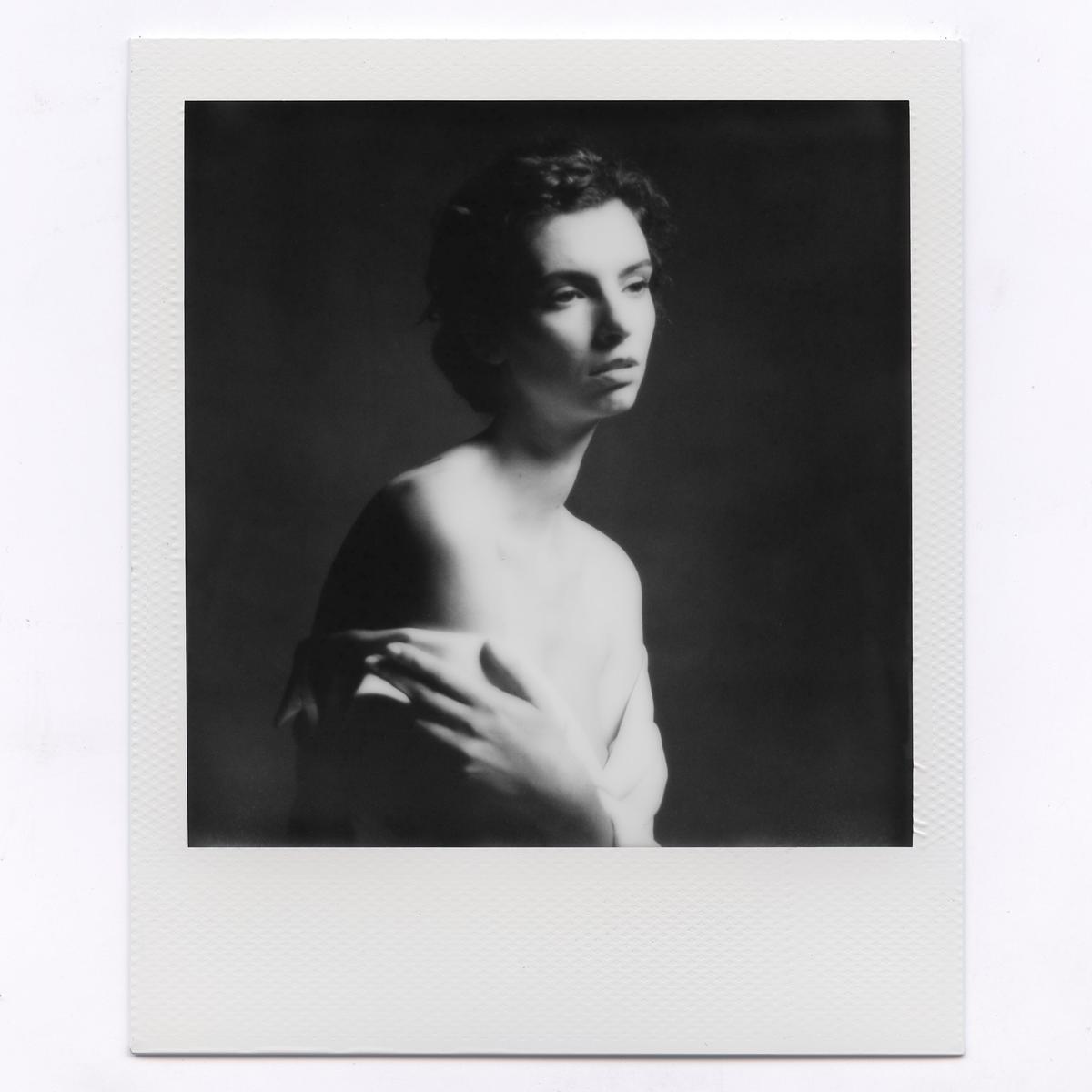A woman with bare shoulders looks away from the camera in a black and white portrait.