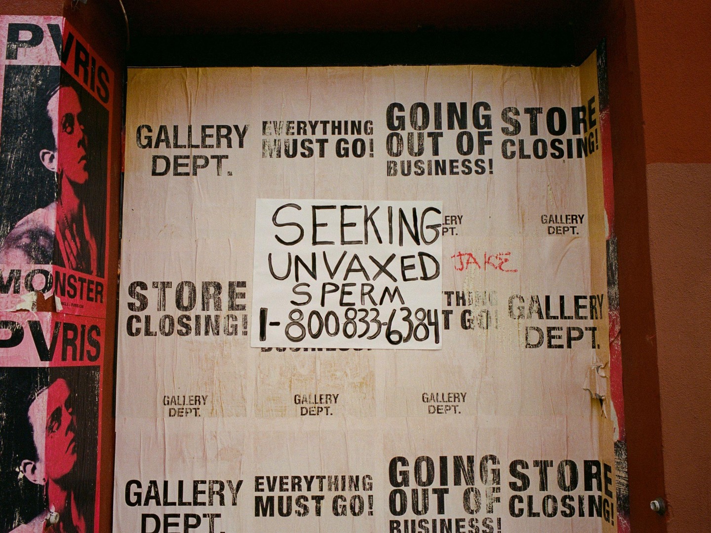 A wall is covered with various posters and flyers, including one advertising a gallery closing and another seeking "unvaxed sperm."