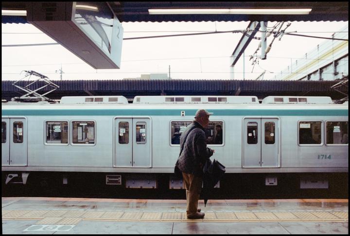 A man stands on a train platform next to a train.