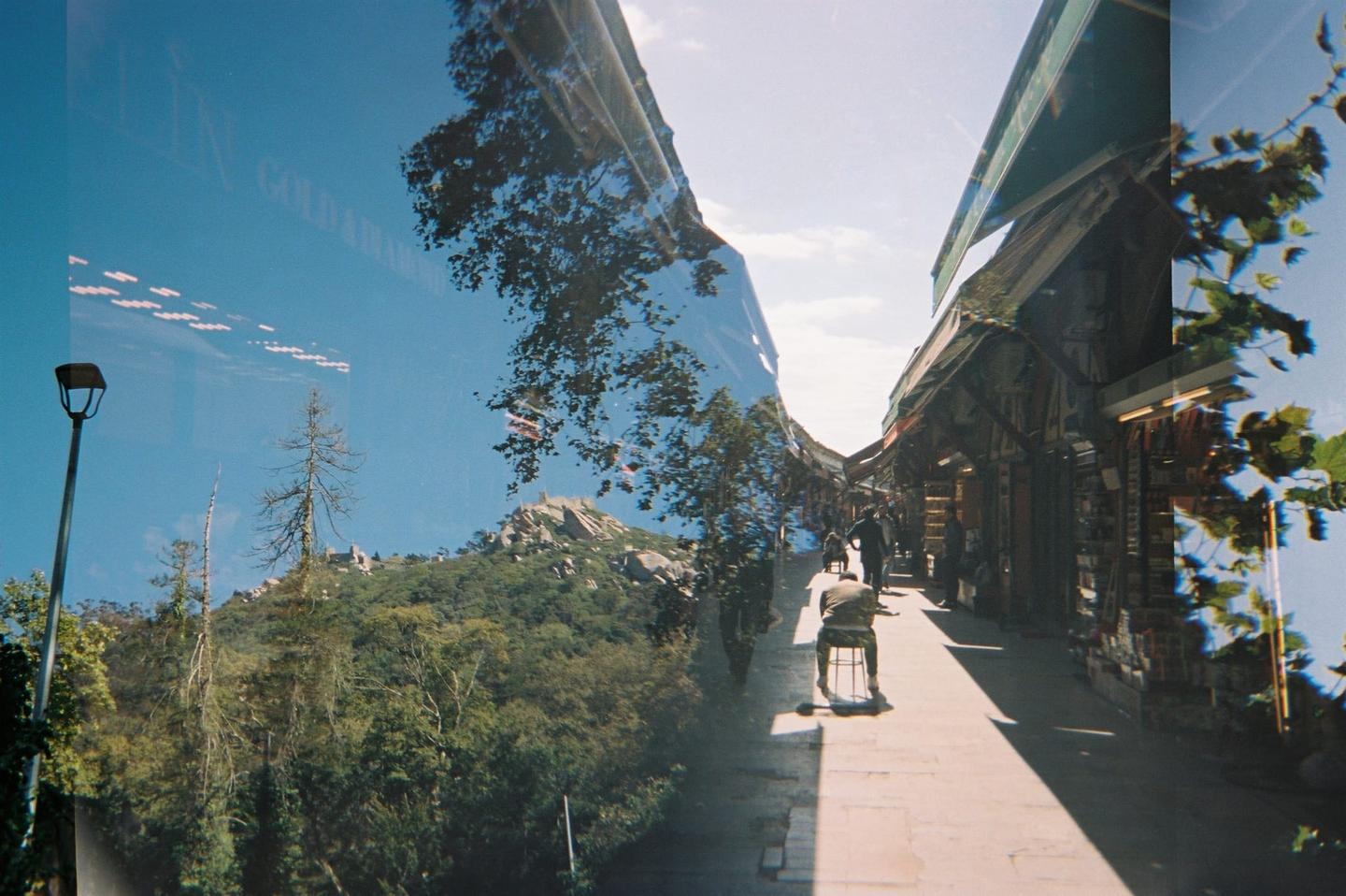 A double exposure shows a mountain landscape with a street lamp and a bazaar street with people.