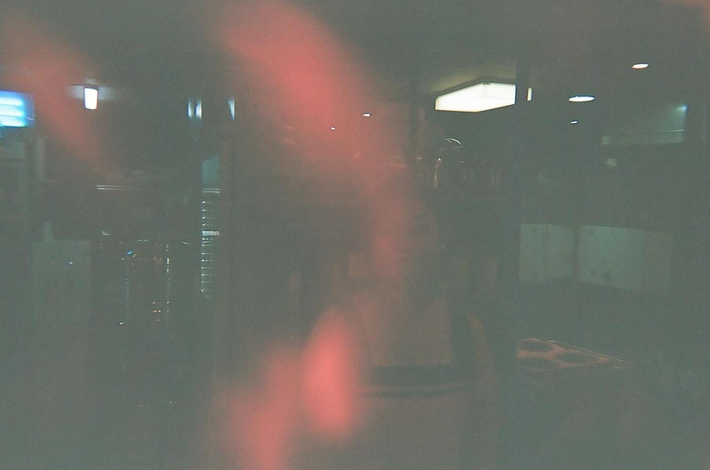A blurry, dark interior with red light leaks shows a person and a pizza box.