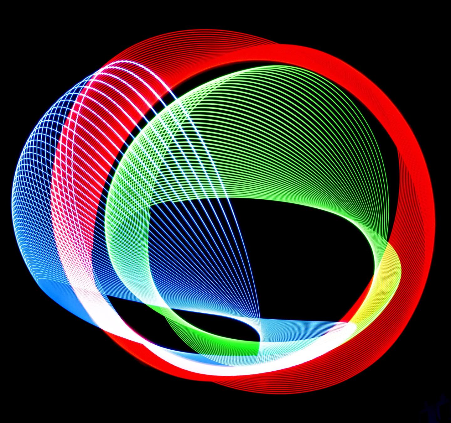 Red, green, and blue light trails overlap to form an abstract pattern against a black background.