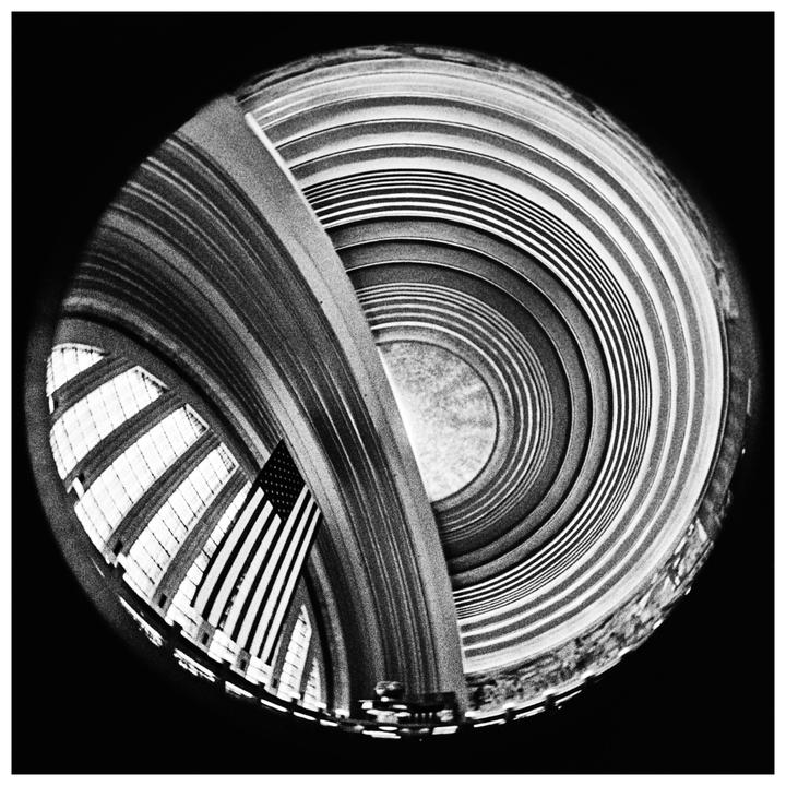 An American flag hangs in a building with a curved ceiling and circular patterns.