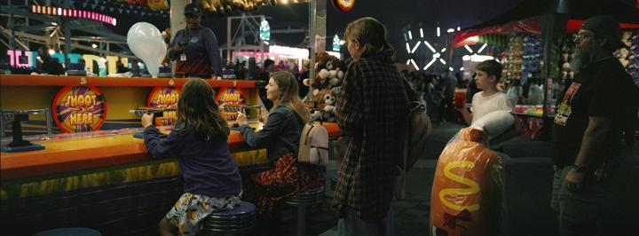 People are playing a shooting game at a fair at night.