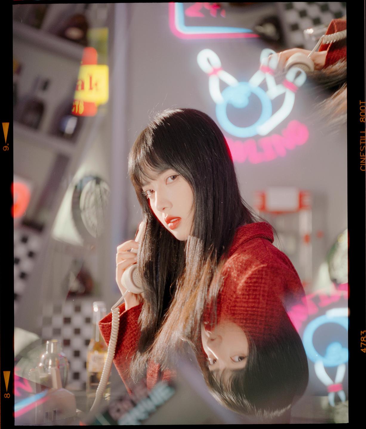 A woman holds a telephone receiver to her ear, with her reflection visible below her.