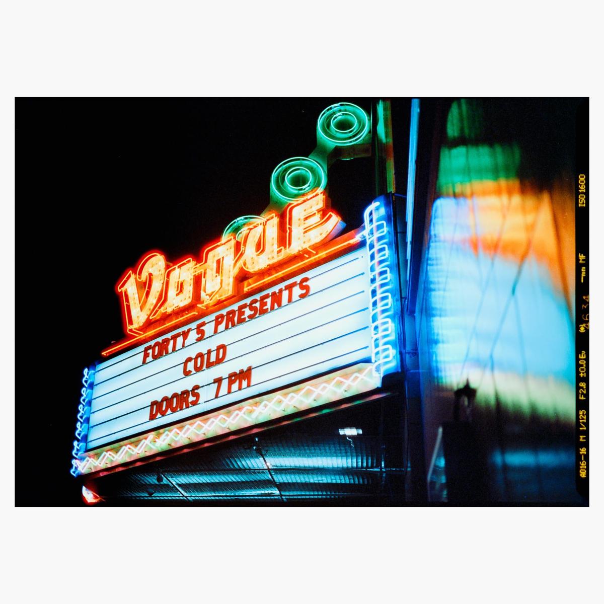 A neon sign for the Vogue theater advertises a concert by Forty 5 Presents and Cold.