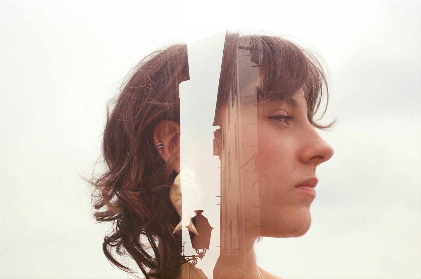 A double exposure shows a woman's profile on the right and the back of her head on the left, with a building and streetlamp visible in the middle.