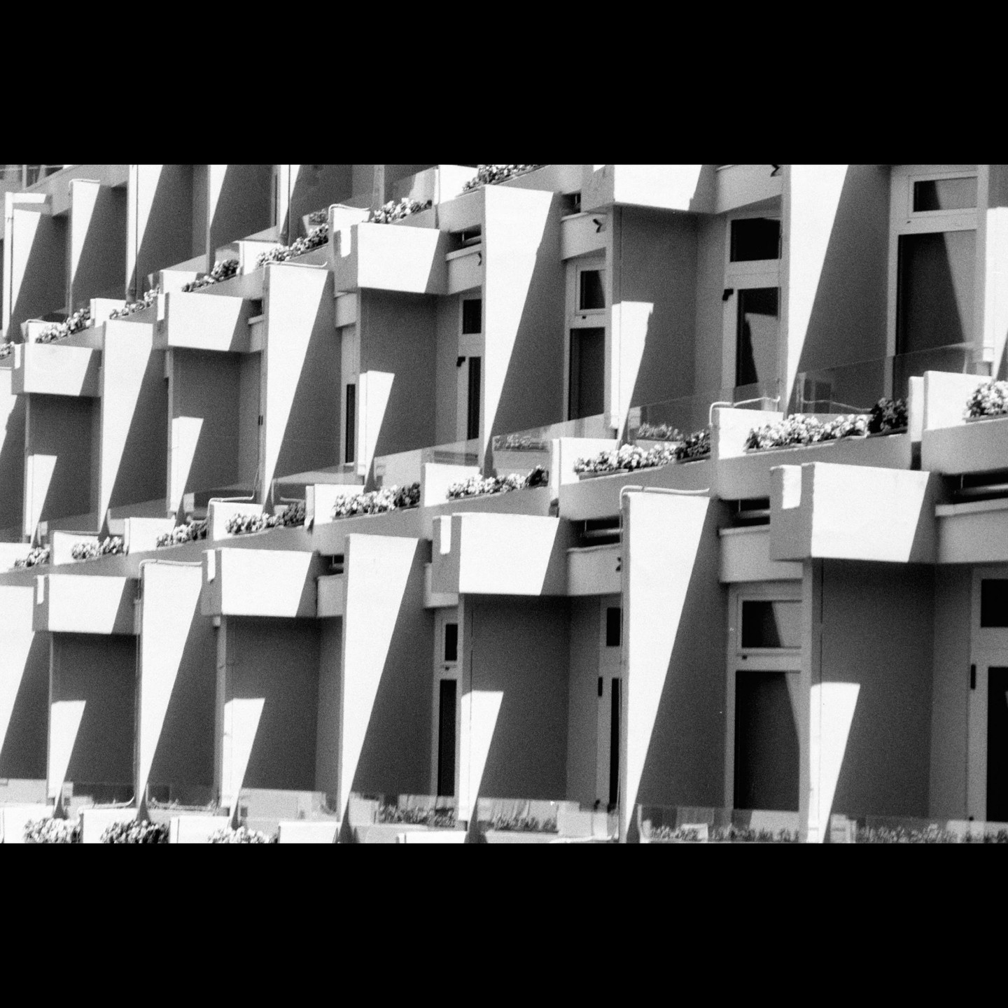 A repeating pattern of balconies with planters is visible on the side of a building.