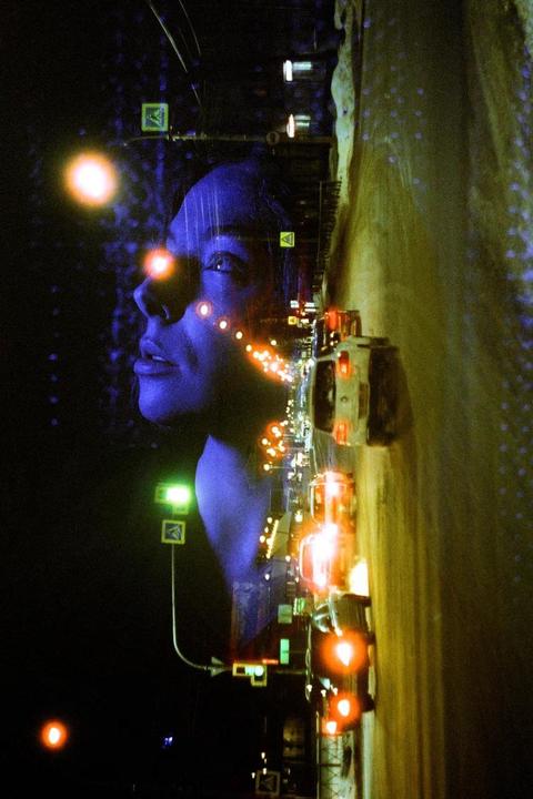 A woman's face is double exposed over a night street scene with cars and streetlights.