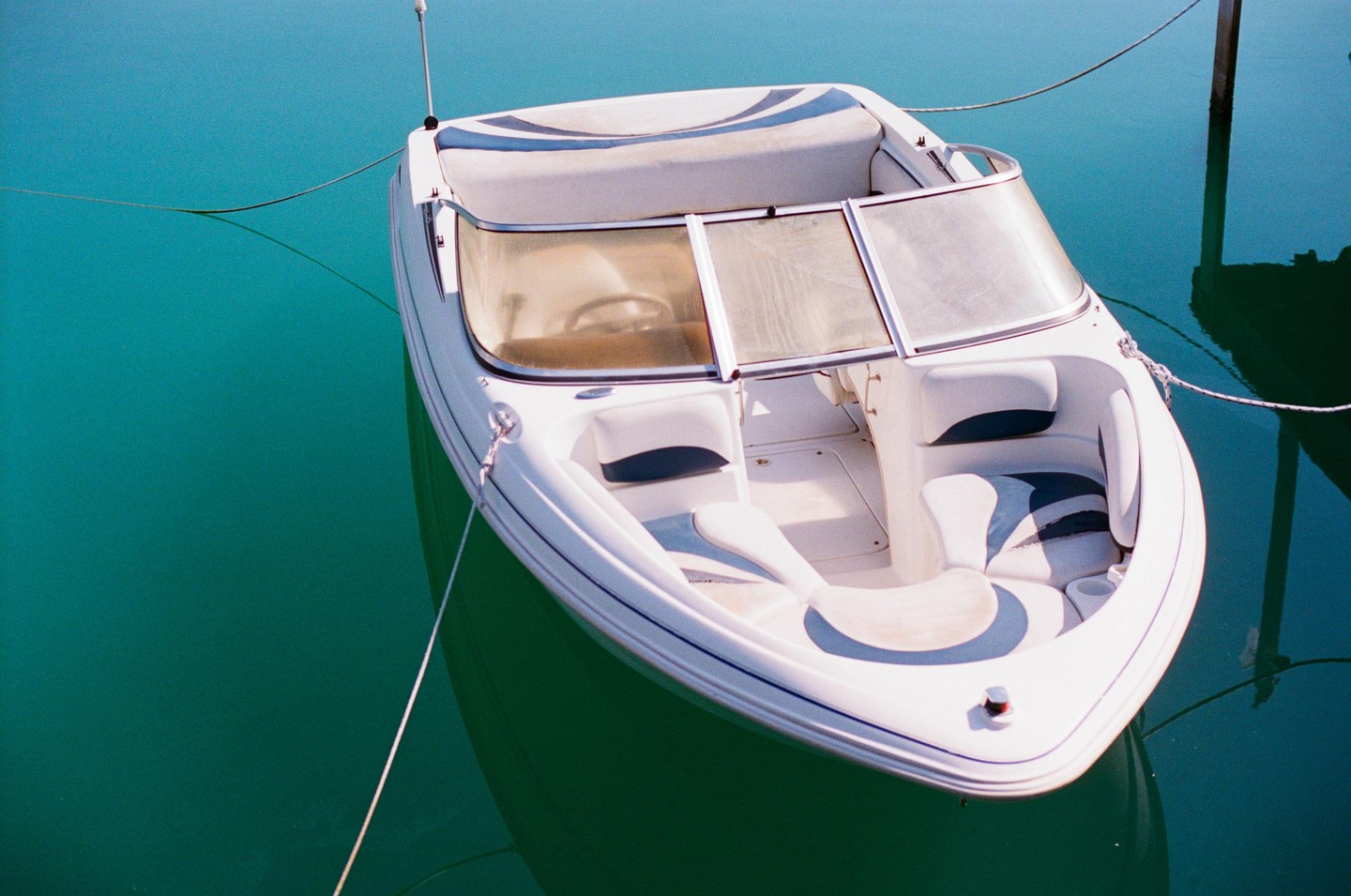 A white motorboat with blue accents is moored in turquoise water.