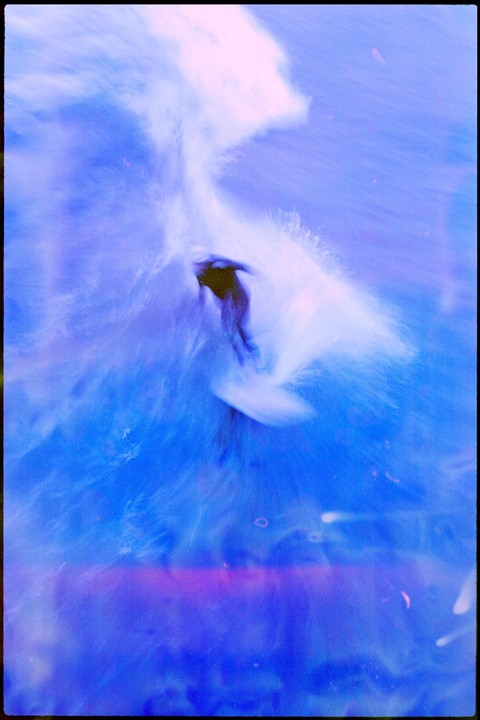 A surfer rides a wave in a blue-toned abstract image.