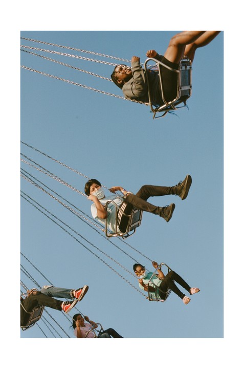 Four people are riding a swing ride against a clear blue sky.
