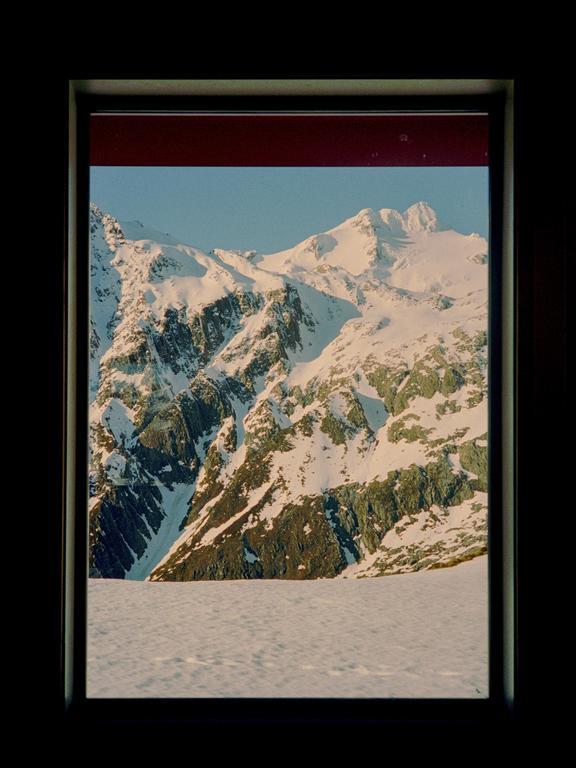 A snow-covered mountain range is visible through a window frame.