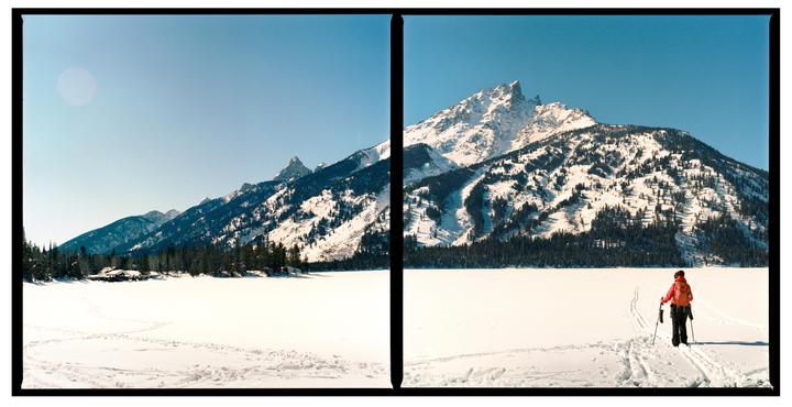 A person cross-country skis across a snow-covered lake toward a large mountain.
