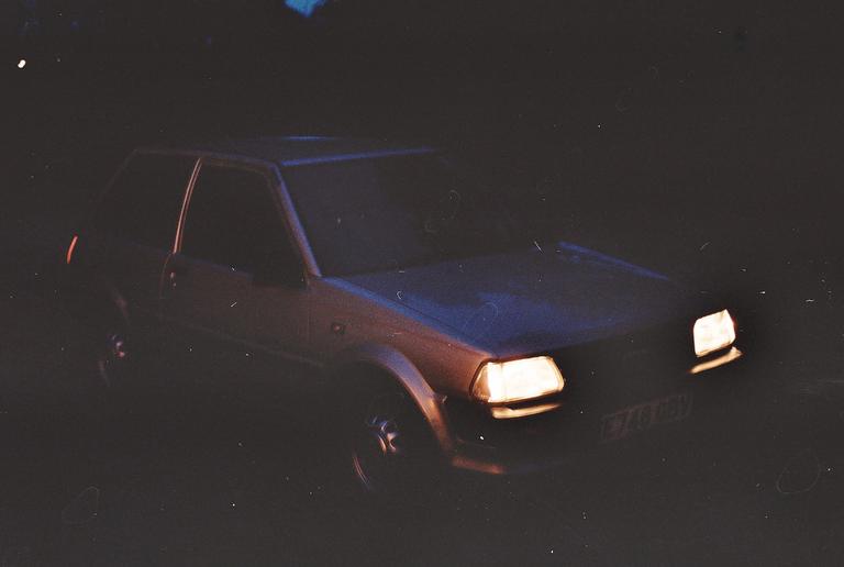 A car with its headlights on is parked in the dark.