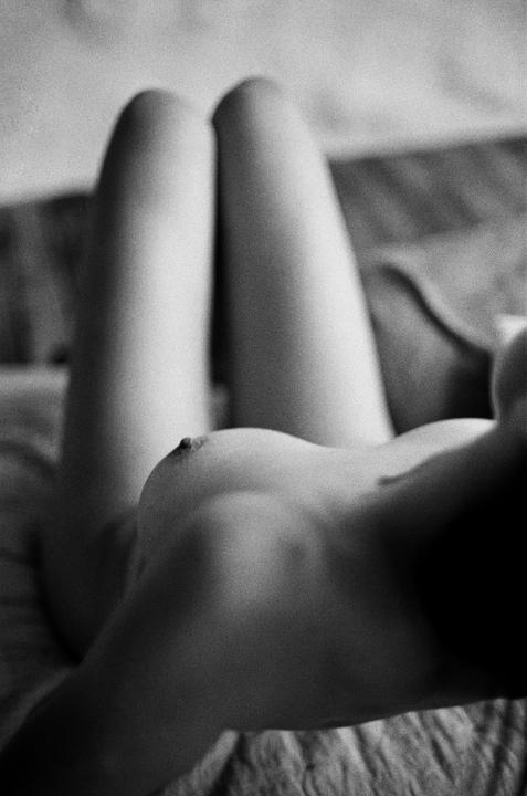 A woman lies on her back with her legs bent and her torso angled towards the viewer.